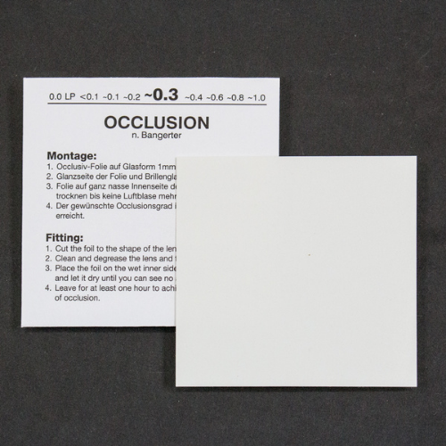 A white instruction card with German nd English text for occlusion lens fitting, shown on a dark textured background with a blank white square overlay in front.