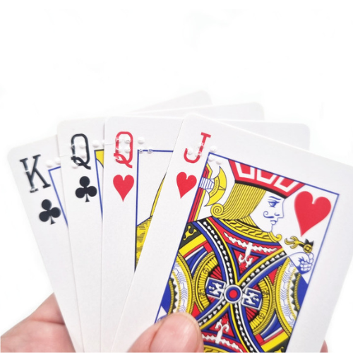 A hand holding a fan of four playing cards, showing a King, Queen, and Jack of hearts and clubs embossed with braille print against a plain white background.