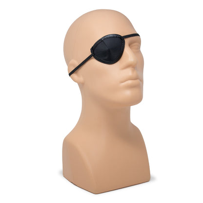 Black eye patch displayed on a beige mannequin head against a plain white background.