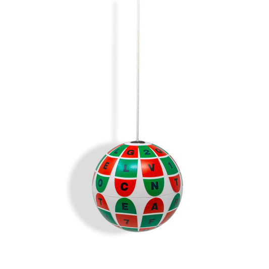 A white soft marsden ball hanging on a white string. The ball features a grid of red and green panels with black letters and numbers, shown against a plain white background.