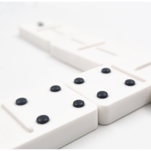 White domino tiles with black raised pips arranged on a white surface, photographed in a close-up studio-style shot.